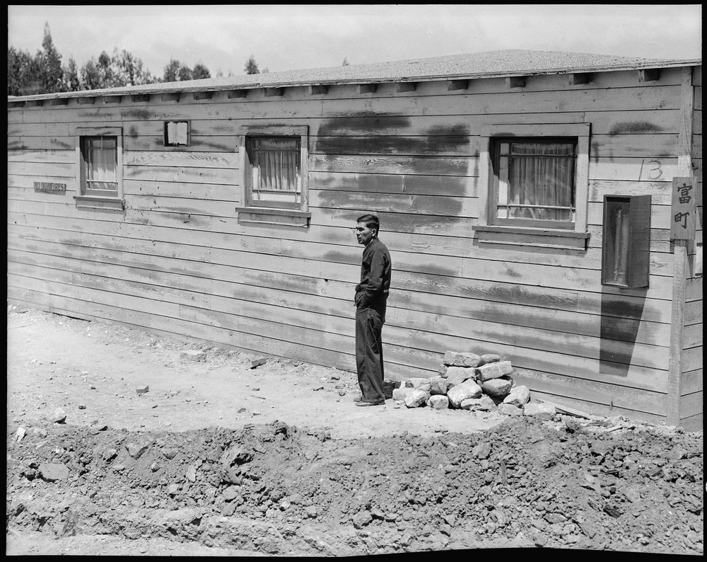 San Bruno, California. Many evacuees suffer from lack of their accustomed activity. The attitude of the man shown in this photograph is typical of the residents in assembly centers, and because there is not much to do and not enough work available, they mill around, they visit, they stroll and they linger to while away the hours.