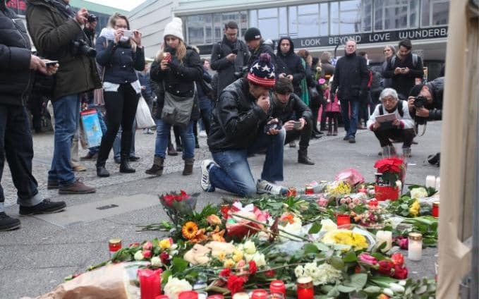  Mourners lay flowers outside the Berlin Christmas market  Credit: Rex Features 